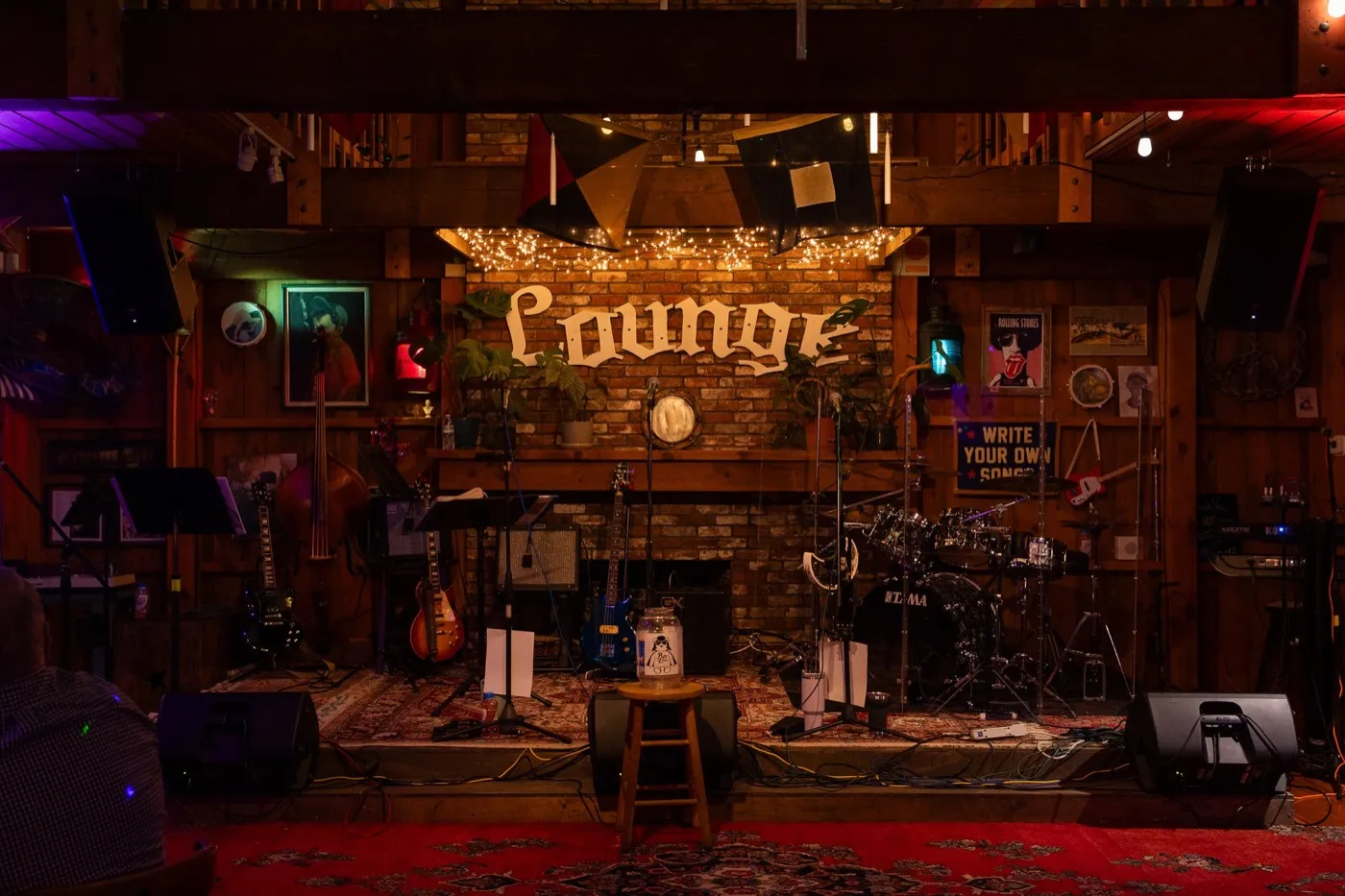 The Lounge stage lit up with string lights, drums and guitars